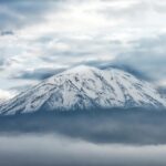 Stunning view of a snowcapped volcanic peak in Arequipa, Peru, surrounded by clouds.