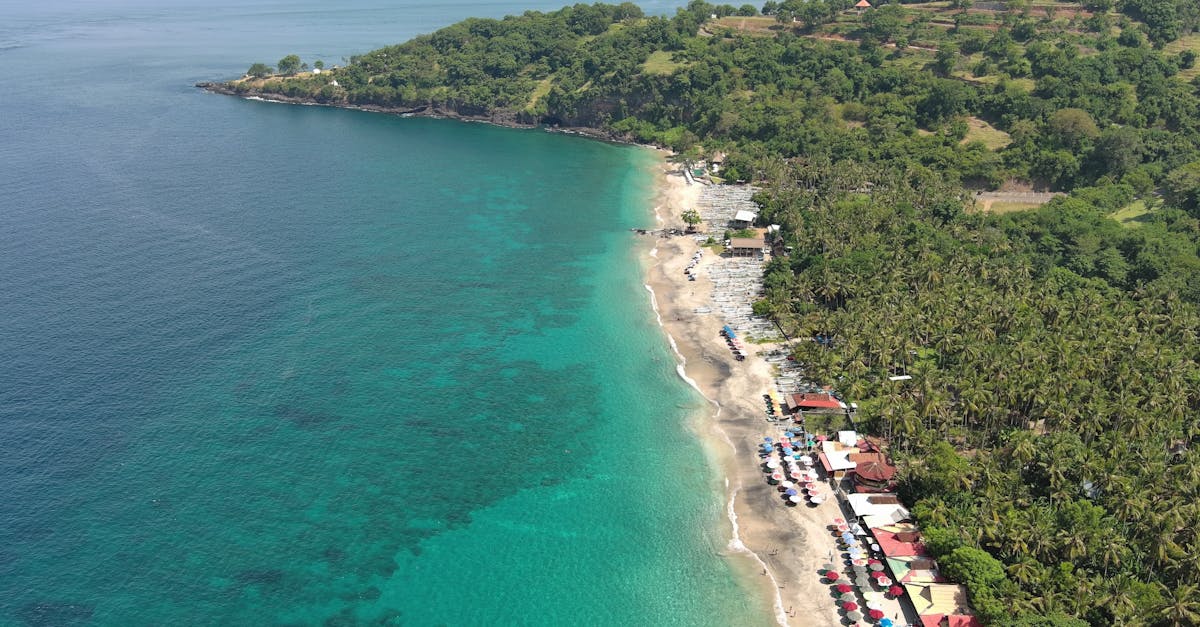 A stunning aerial view of a tropical beach in Bali with turquoise waters and lush greenery.