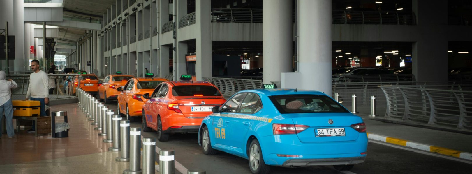 Vibrant taxis lined up at Istanbul Airport arrival terminal with passengers and drivers interacting.